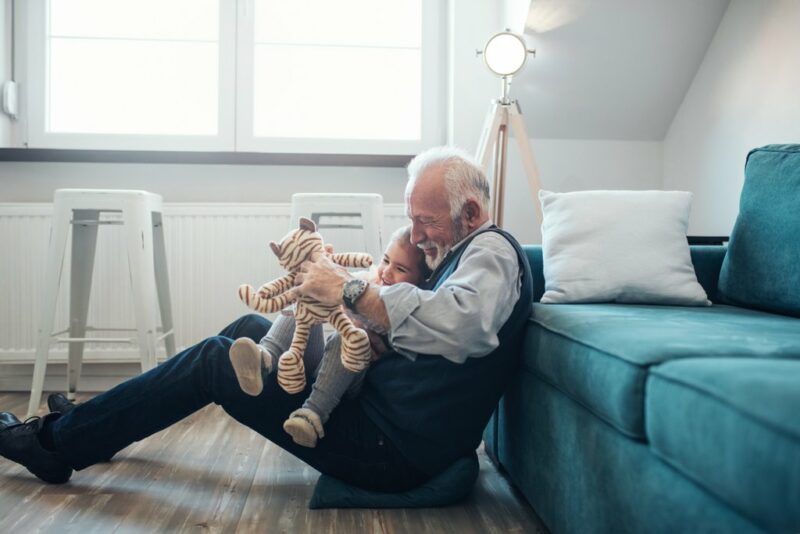 mies istuu lattialla sohvan edessä lapsi sylissä
