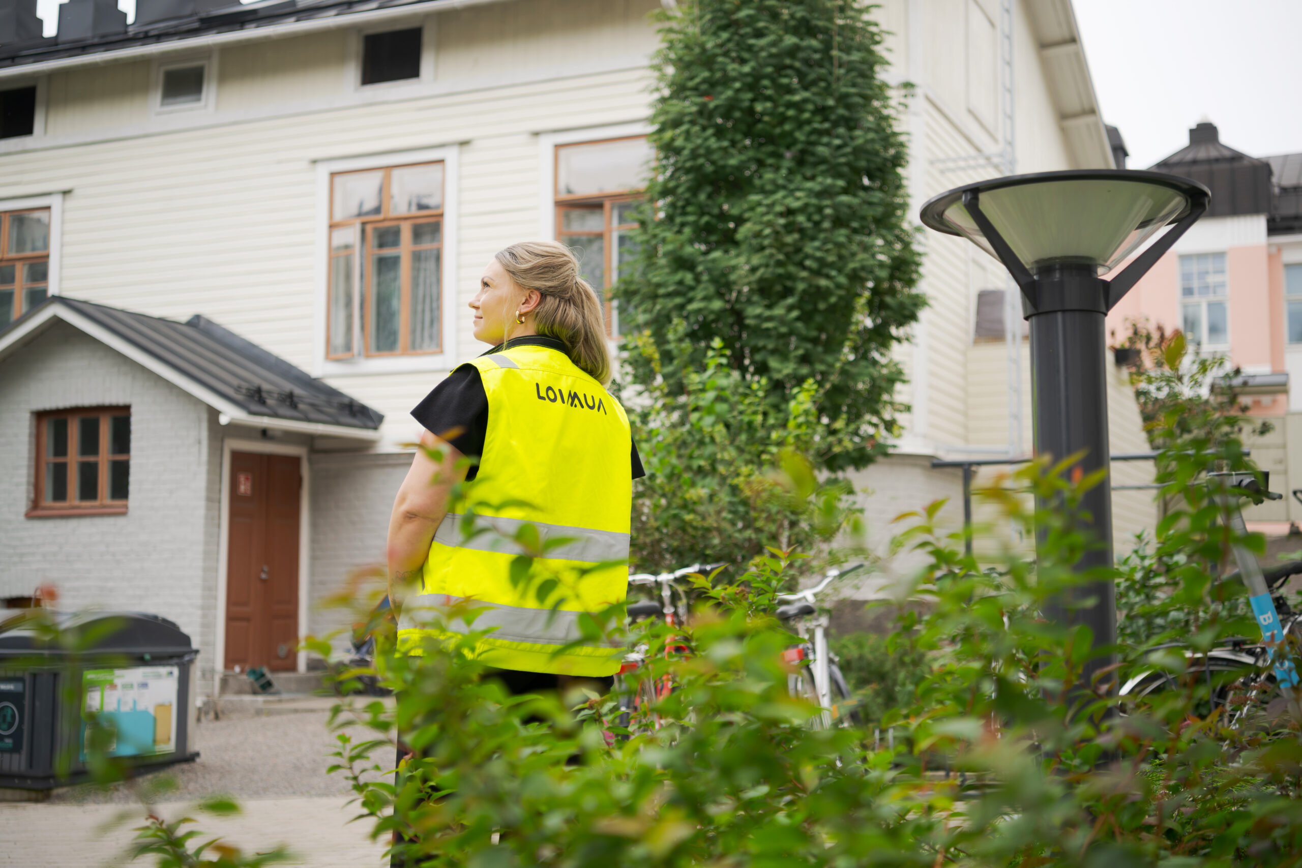 Nainen seisoo ulkona Loimuan työliivi päällä.